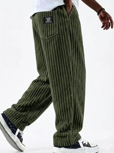 Green corduroy pants worn by a person on a white background