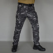 Front view of a model wearing gray and black patterned cargo pants with a black belt and black lace-up boots against a gray background.⠋