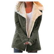 Woman wearing an olive green coat with wide cream fleece-look lapels, front pockets and cuff tabs over a white top and dark trousers