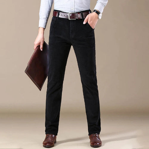 Person wearing black pants and holding a brown folder against a beige background