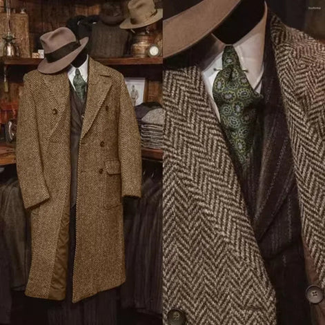 A vintage-style men's suit ensemble displayed on a mannequin in a shop setting, featuring a brown herringbone double-breasted overcoat, a dark patterned vest, 