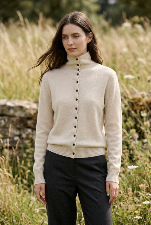 A person wearing a light beige ribbed turtleneck cardigan sweater with black buttons, photographed in a cafe setting. The text 'WinvyNee' is overlaid in the top left corner.