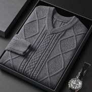 Gray patterned sweater in a black box with a watch on a dark surface