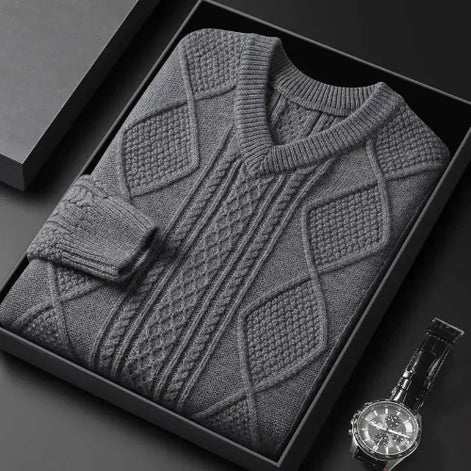 Gray patterned sweater in a black box with a watch on a dark surface