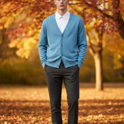 Blue cardigan over a white shirt on a wooden hanger against a dark background
