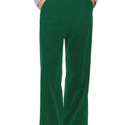 A person wearing high-waisted, wide-leg green corduroy trousers, styled with a light lavender ruffled shirt and black leather shoes, 