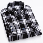 A folded long-sleeve plaid button-up shirt in black, white, and gray, with blue buttons, shown on a clean white background.