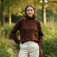 Person wearing a brown textured sweater with a blurred green background