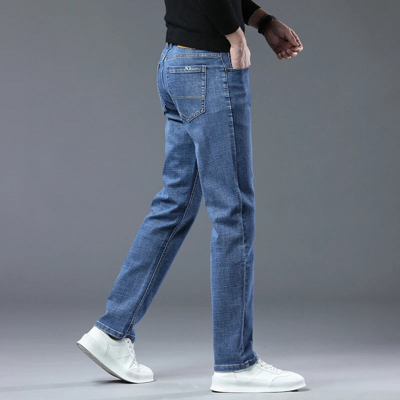 Person wearing blue jeans and white sneakers on a gray background