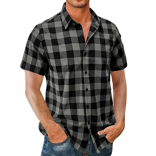 A man wearing a short-sleeve button-up shirt with a black and gray buffalo plaid pattern, paired with blue jeans, shown against a plain white background.