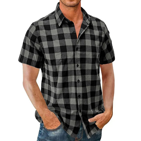 A man wearing a short-sleeve button-up shirt with a black and gray buffalo plaid pattern, paired with blue jeans, shown against a plain white background.