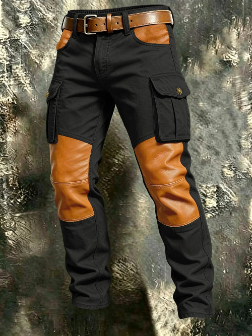 Black cargo pants with tan contrast panels at the knees and front pockets, flap thigh pockets, and a brown belt against a textured gray background.
