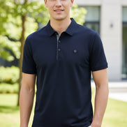 Navy blue polo shirt on a hanger with a hand touching it, brand logo visible