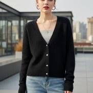 A person wearing a dark fuzzy knit cardigan over a light gray top and light blue jeans, 