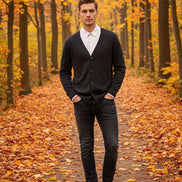 Black cardigan over a white shirt on a wooden hanger against a wooden panel background
