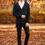 Black cardigan over a white shirt on a wooden hanger against a wooden panel background