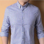 Person wearing a blue and white checkered shirt against a beige background