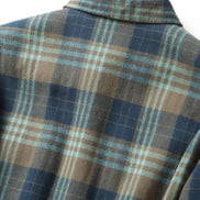 A close-up of a plaid flannel shirt on a mannequin, featuring a pattern of navy blue, brown, and light blue stripes.