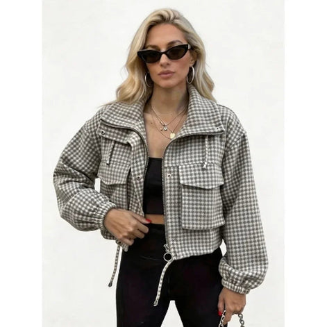 Woman wearing a gray and white checked utility jacket with chest flap pockets, a ring-pull zipper and drawcord hem over a black top and trousers