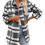 Woman wearing a gray and white plaid shirt with jeans, against a white background.