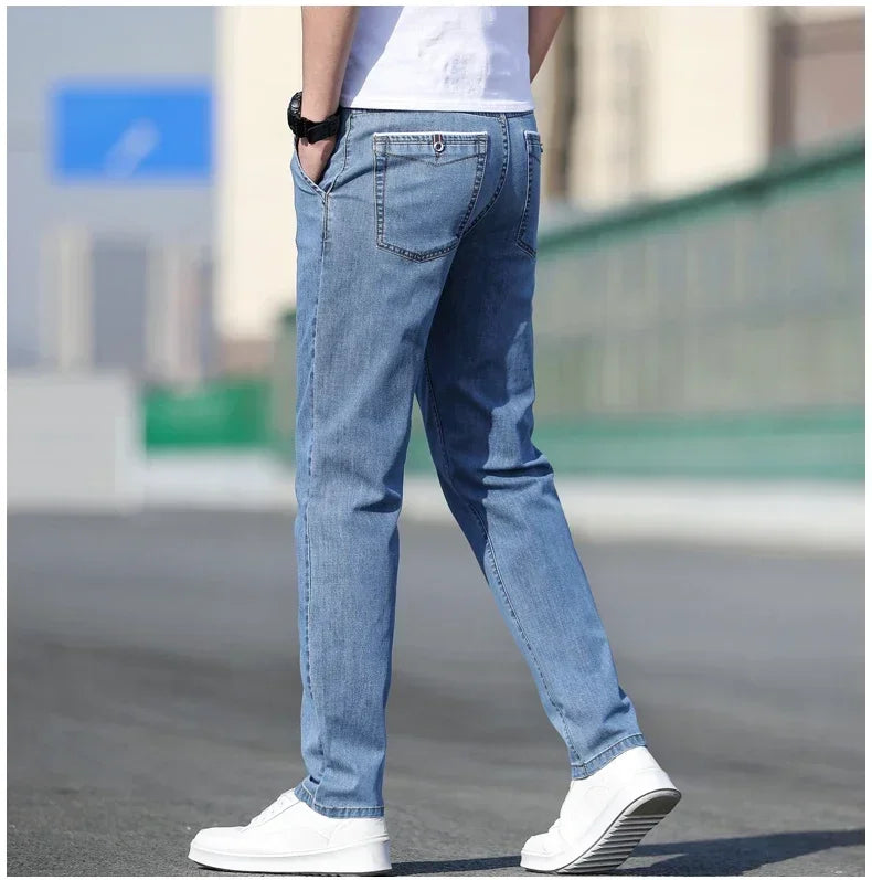 Person wearing light blue jeans and white sneakers on a blurred street background