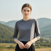 Person wearing a gray long-sleeve shirt and black pants against a neutral background