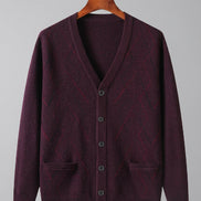 A men's knit cardigan sweater in a deep plum purple color, hanging on a wooden hanger against a white background. The cardigan features a V-neck, button-up front, and two front patch pockets.