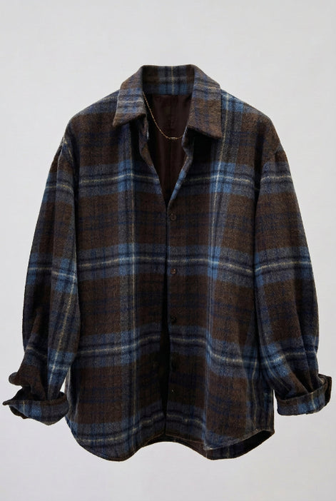 A brown and blue plaid button-up shirt jacket displayed on a black hanger against a light-colored indoor background.