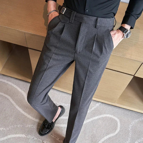 Person wearing gray dress pants and black shoes on a wooden floor.
