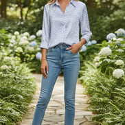 Woman wearing a light blue patterned shirt against a plain background
