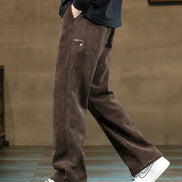 Person wearing brown pants and white sneakers on a neutral background