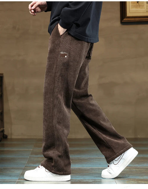 Person wearing brown pants and white sneakers on a neutral background