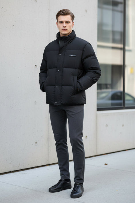 A black puffer jacket hanging on a clothing rack in a retail store setting, with promotional graphic overlays on the left highlighting warmth, softness, and down content. The jacket has a high collar, front zipper and snap closure, and a small chest label.