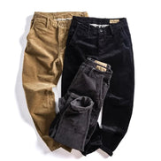 Three pairs of corduroy pants in tan, black, and charcoal gray, arranged in a flat-lay on a white background.
