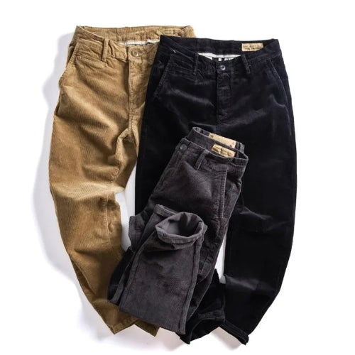 Three pairs of corduroy pants in tan, black, and charcoal gray, arranged in a flat-lay on a white background.