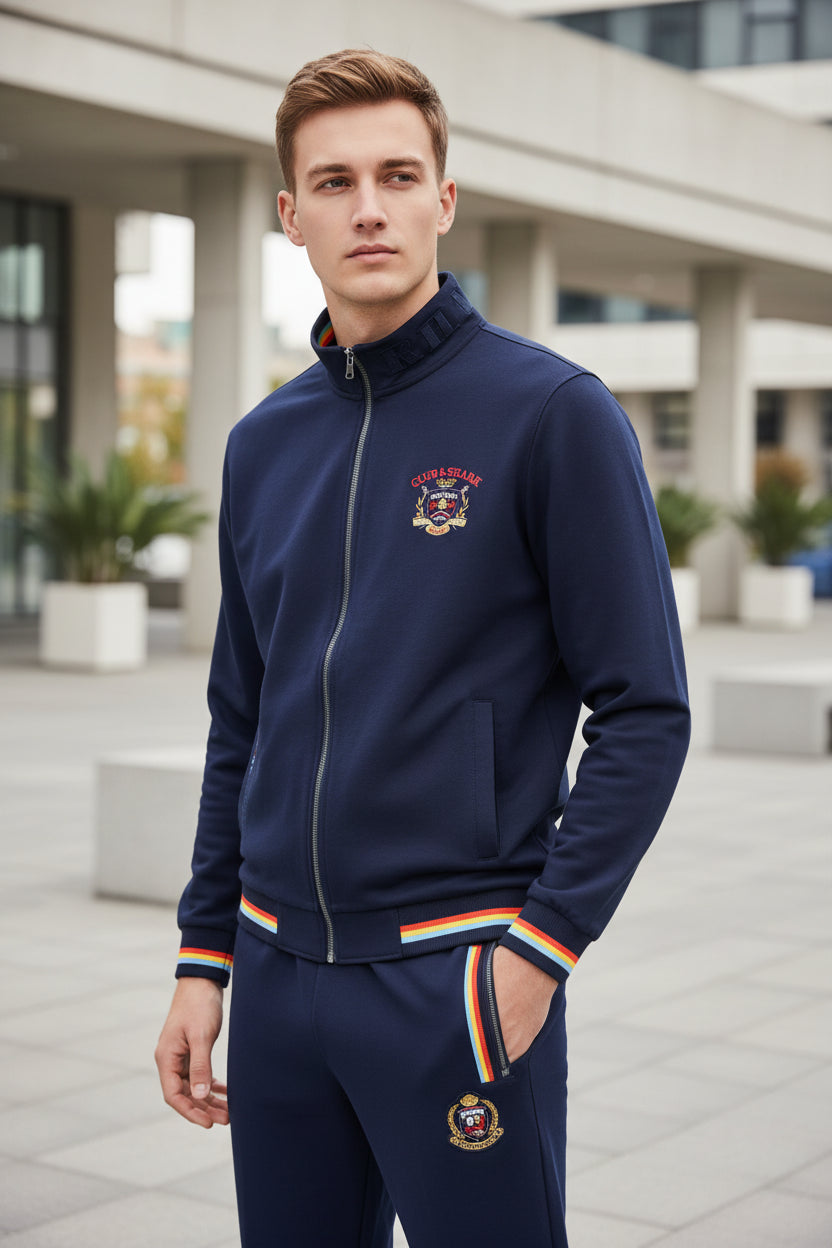 A two-piece navy blue tracksuit set featuring a zip-up jacket and matching pants. The jacket and pants have red, yellow, and white striped accents at the cuffs, hem, and waistband.