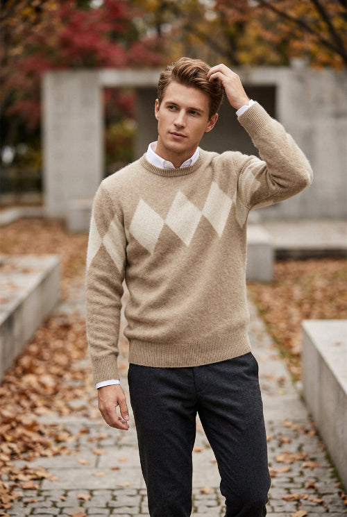 A beige and cream argyle knit sweater displayed on a wooden hanger over a white collared shirt, set against a solid gray background.