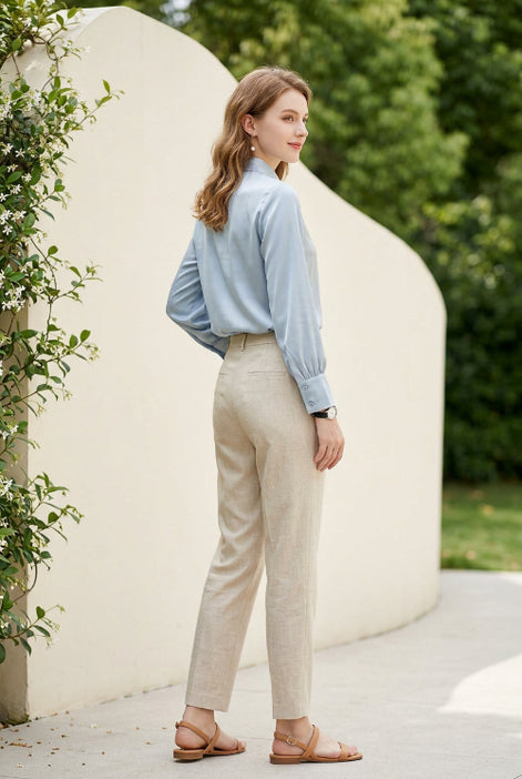 Woman wearing a light gray blouse with long sleeves against a neutral background