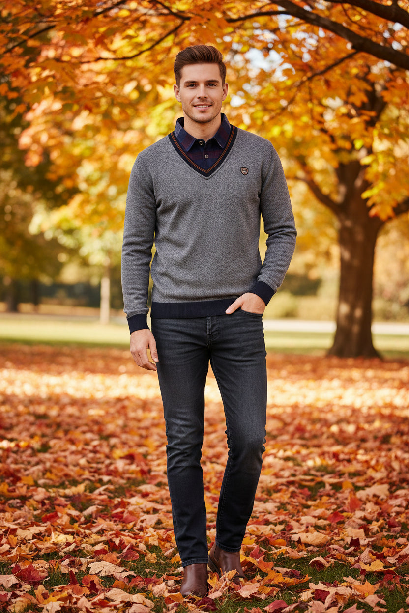Folded gray sweater with navy collar on a snowy background