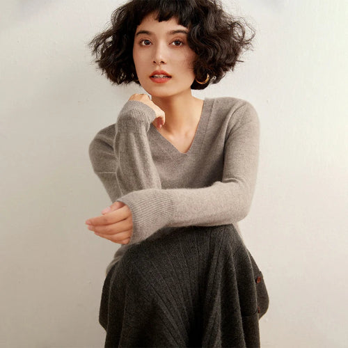 Woman wearing a gray sweater against a plain background