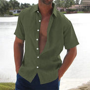 Man wearing an open green shirt by a body of water