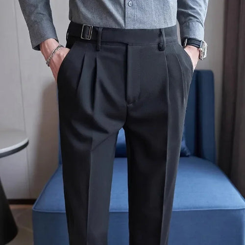 Person wearing dark gray pleated pants and a light gray shirt in a room with a blue chair.