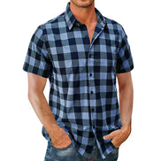 A man wearing a short-sleeve button-up plaid shirt in navy and light blue, paired with blue jeans, shown against a plain white background.