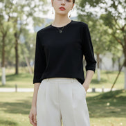 Person wearing a black t-shirt and white pants sitting on a wooden floor.
