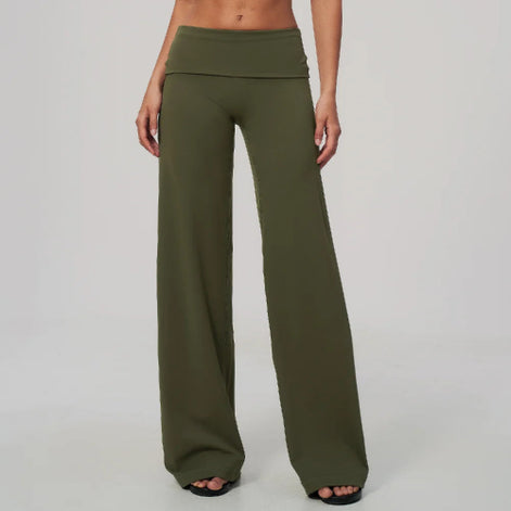 A model is wearing olive green wide-leg lounge pants with a high-waisted, draped waistband, shown from the waist down against a light gray studio background.