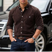 A man wearing a dark brown long-sleeve button-down shirt with rolled-up sleeves, 
