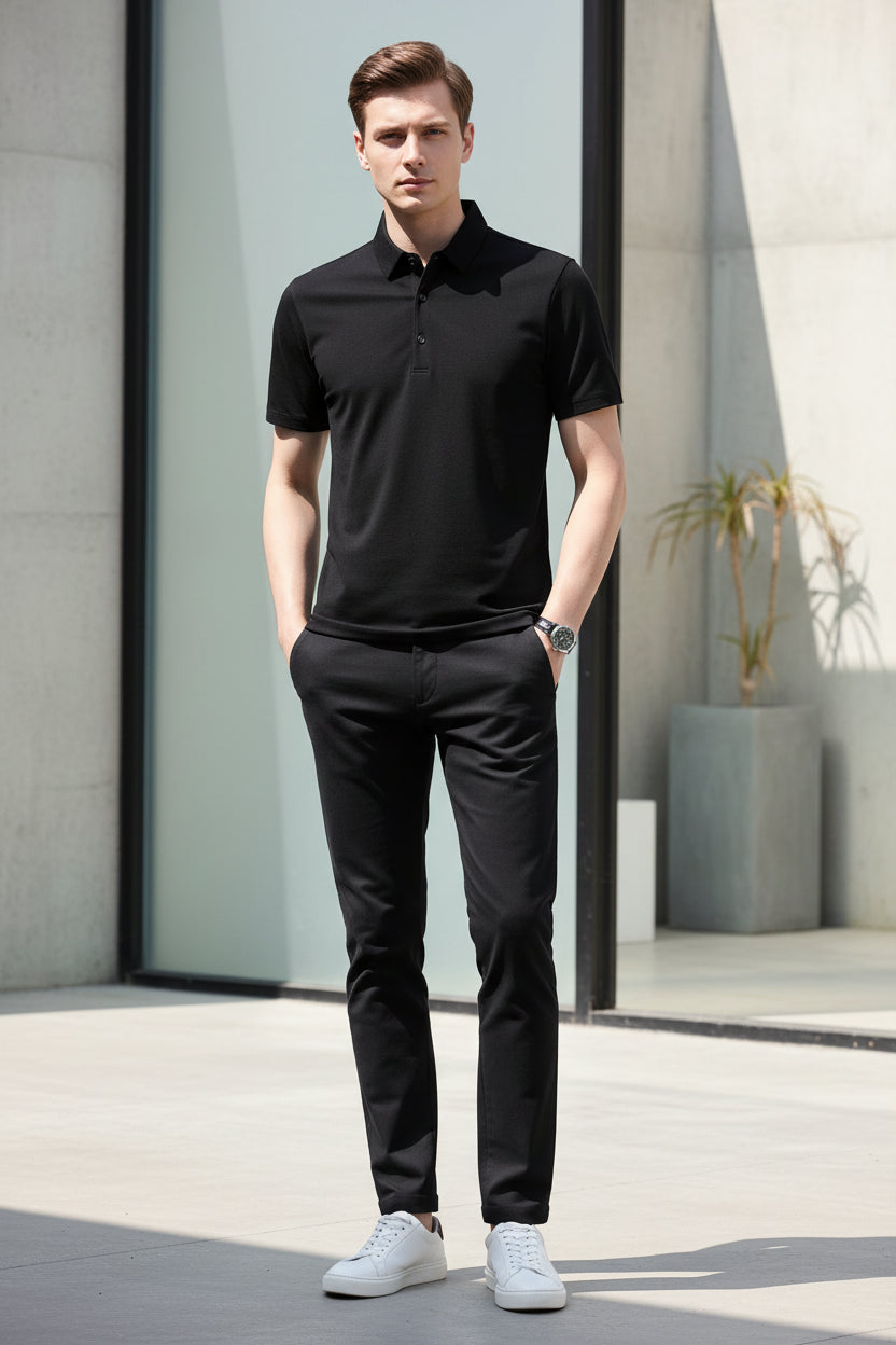 Person wearing a black polo shirt against a gray background