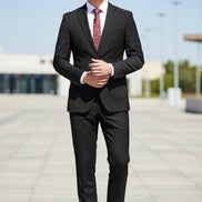 Black suit with a red patterned tie on a mannequin, paired with brown shoes on a white background.