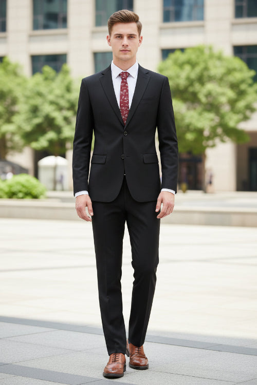 Black suit with a red patterned tie on a mannequin, paired with brown shoes on a white background.