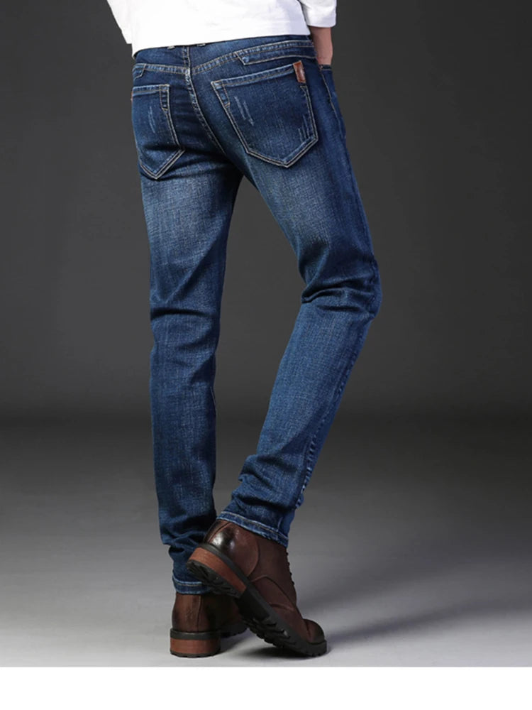 Person wearing blue jeans and brown shoes on a gray background